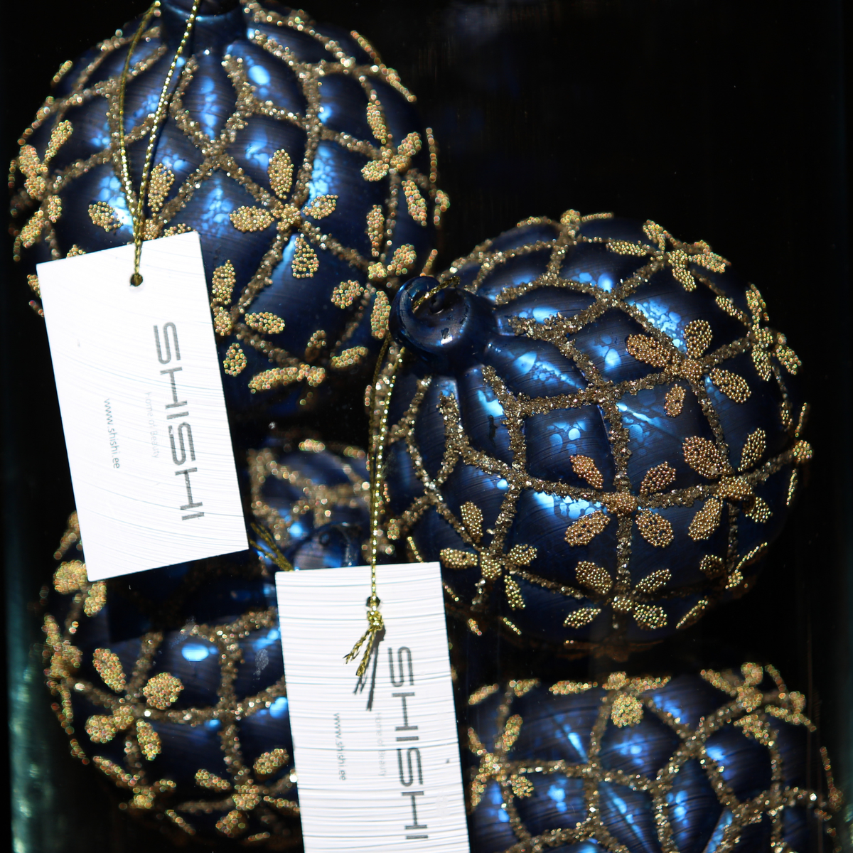 Three metallic blue Christmas ornaments decorated with gold glitter floral patterns, each with a white hanging tag printed with the brand name 'SHISHI'.