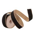 A roll of black velvet ribbon with a tan stitched edge, unspooled into a loop on a plain white background.