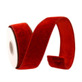 A roll of red velvet ribbon, partially unrolled to show its plush texture and stitched edges, set against a plain white background.