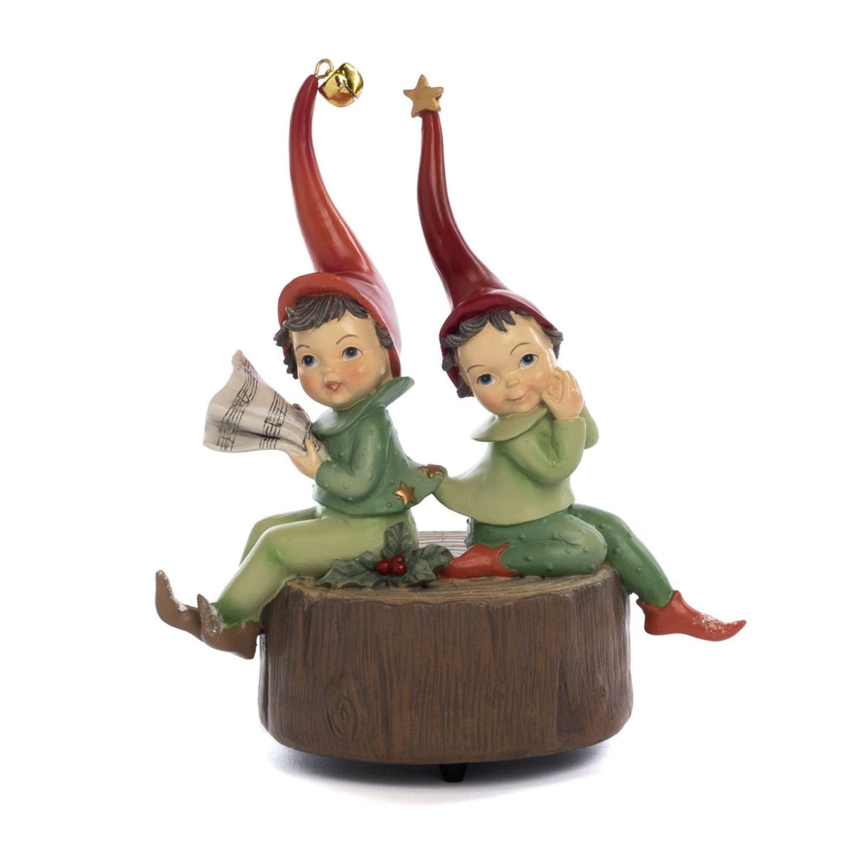 A Christmas-themed figurine depicting two helper pixies children dressed as elves sitting on a wooden rustic stump. One elf reads a sheet music, while the other touches her chin, shown on a plain white background - 19 cm