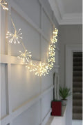 Warm white starburst LED fairy string lights draped across a white paneled wall in a home hallway.